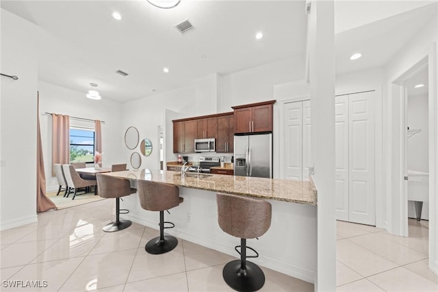 3410 NW 17th Ln, Cape Coral, FL 33993 - kitchen with stainless steel appliances, a kitchen bar, light tile patterned floors, light stone counters, and recessed lighting