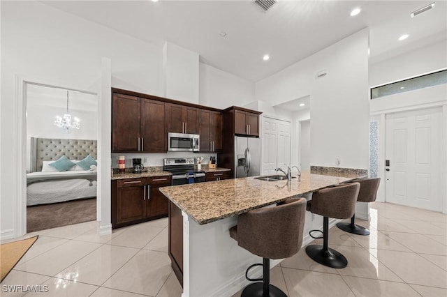 3410 NW 17th Ln, Cape Coral, FL 33993 - kitchen with appliances with stainless steel finishes, a kitchen breakfast bar, light tile patterned floors, a sink, and a high ceiling