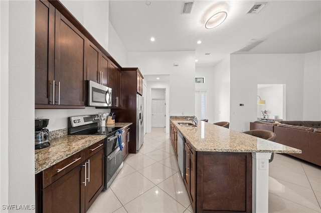 3410 NW 17th Ln, Cape Coral, FL 33993 - kitchen featuring appliances with stainless steel finishes, a sink, open floor plan, light stone countertops, and a breakfast bar area