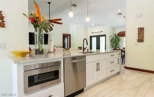 2535 River Reach Dr, Naples, FL 34104 - kitchen featuring appliances with stainless steel finishes, a sink, light marble finish flooring, white cabinets, and hanging light fixtures