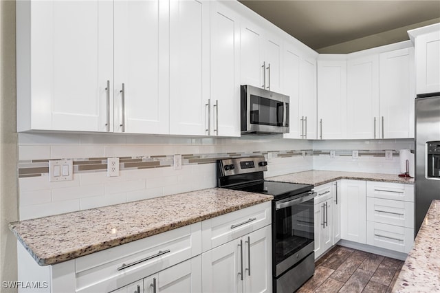 1049 Solar Ct, Labelle, FL 33935 - kitchen with appliances with stainless steel finishes, tasteful backsplash, white cabinets, dark wood-style flooring, and light stone countertops