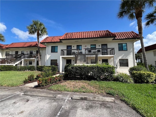 4186 27th Ct SW Unit 105, Naples, FL 34116 - view of front of house featuring a tile roof, stucco siding, a balcony, and a front lawn