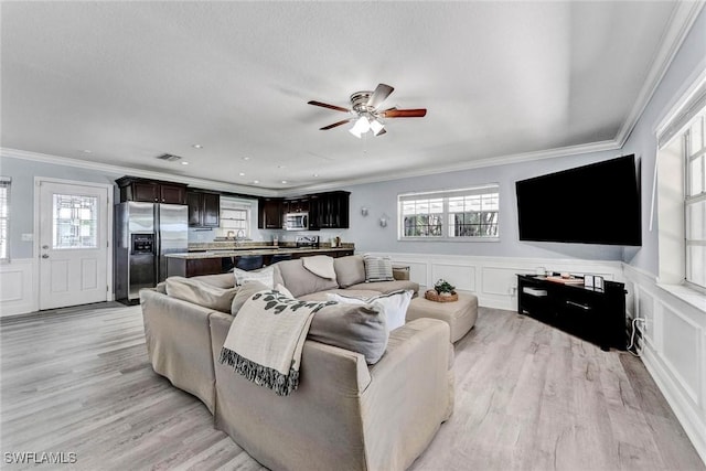 7709 1st Ter, Lake Worth, FL 33463 - living area with light wood-style flooring, a ceiling fan, crown molding, plenty of natural light, and a decorative wall