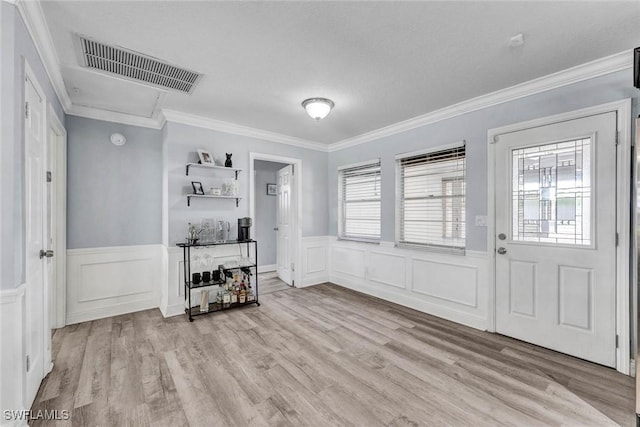 7709 1st Ter, Lake Worth, FL 33463 - foyer with a wainscoted wall, ornamental molding, light wood-style flooring, and a decorative wall