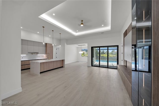 419 NW 7th Ave, Cape Coral, FL 33993 - unfurnished living room featuring a raised ceiling, light wood finished floors, recessed lighting, a sink, and baseboards