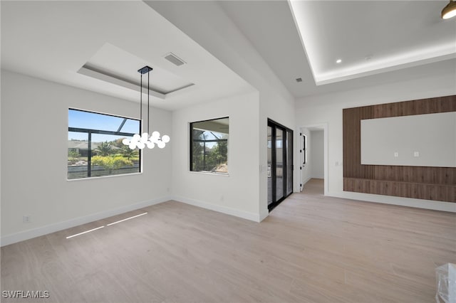 419 NW 7th Ave, Cape Coral, FL 33993 - empty room featuring a raised ceiling, light wood finished floors, a chandelier, and baseboards