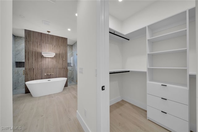 419 NW 7th Ave, Cape Coral, FL 33993 - bathroom featuring wood finished floors, a walk in closet, baseboards, a soaking tub, and recessed lighting