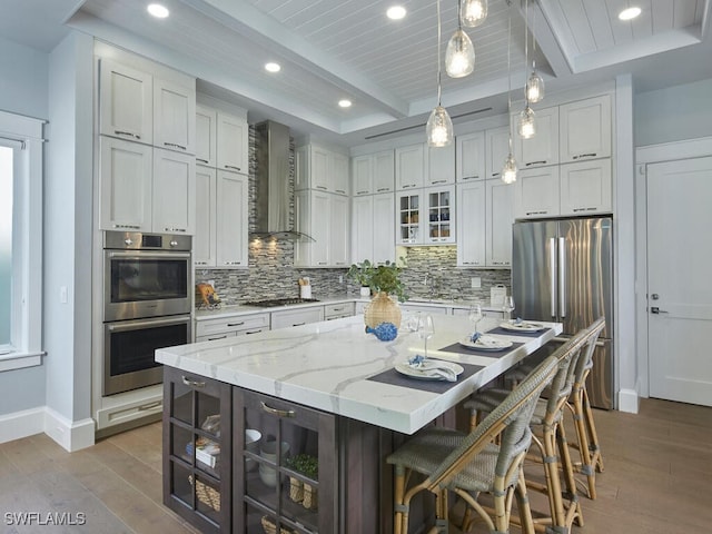 242 2nd Ave S, Naples, FL 34102 - kitchen with wall chimney range hood, stainless steel appliances, wood finished floors, decorative backsplash, and recessed lighting