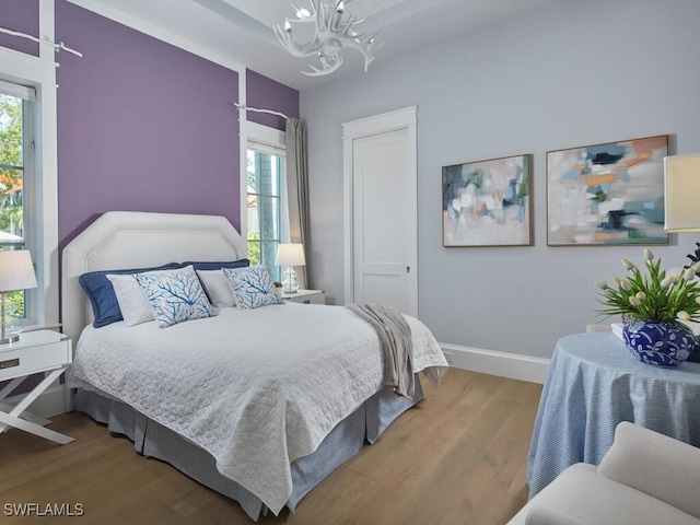 242 2nd Ave S, Naples, FL 34102 - bedroom with a chandelier, multiple windows, wood finished floors, and baseboards