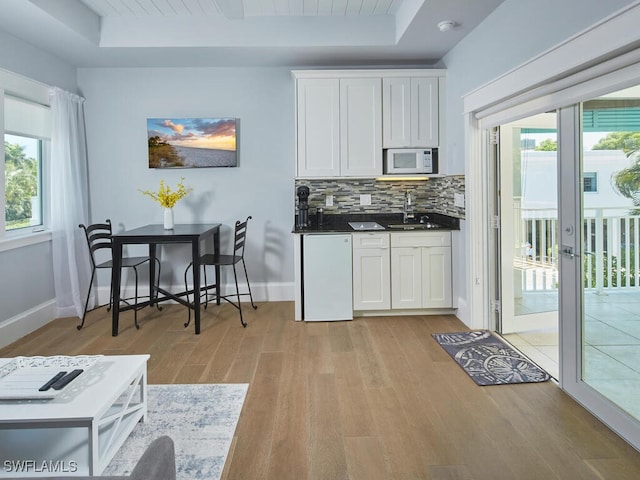 242 2nd Ave S, Naples, FL 34102 - kitchen featuring white microwave, a sink, light wood-style flooring, and a raised ceiling