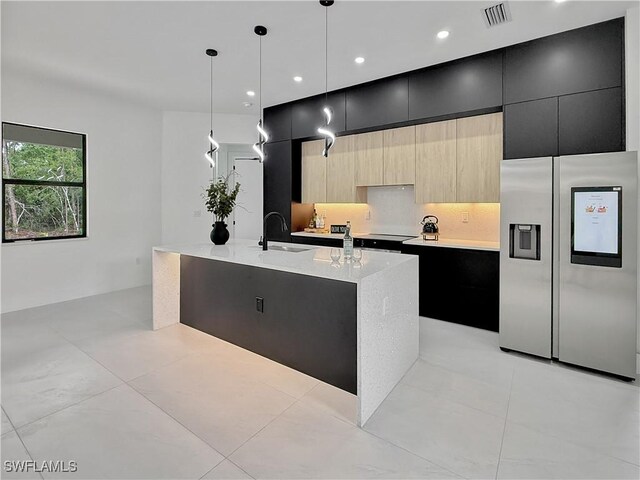 3247 72nd Ave NE, Naples, FL 34120 - kitchen featuring stainless steel fridge, dark cabinetry, a sink, modern cabinets, and an island with sink