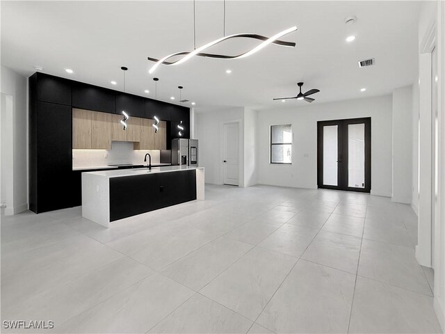 3247 72nd Ave NE, Naples, FL 34120 - kitchen featuring modern cabinets, stainless steel refrigerator with ice dispenser, open floor plan, a center island with sink, and light countertops