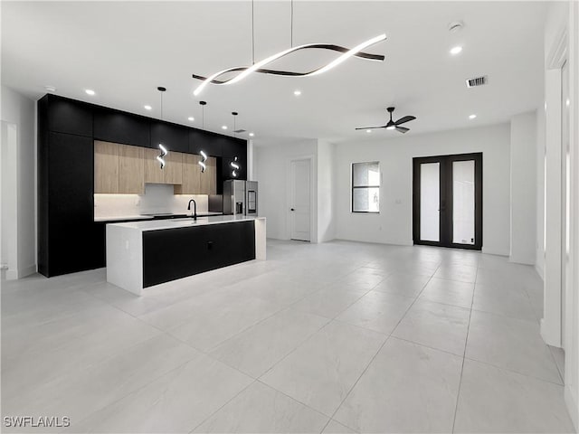 3247 72nd Ave NE, Naples, FL 34120 - kitchen featuring modern cabinets, stainless steel refrigerator with ice dispenser, open floor plan, a center island with sink, and light countertops