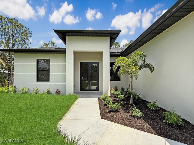 3247 72nd Ave NE, Naples, FL 34120 - entrance to property with french doors, stucco siding, and a lawn