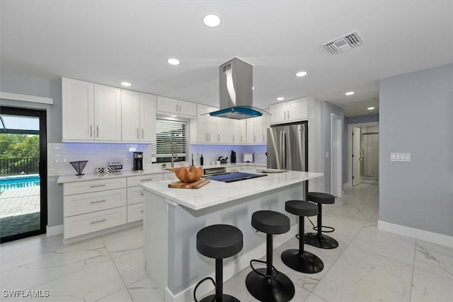 52 Fairview Blvd, Fort Myers Beach, FL 33931 - kitchen featuring freestanding refrigerator, light marble finish floors, island exhaust hood, white cabinetry, and recessed lighting