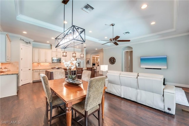 23778 Pebble Pointe Ln, Estero, FL 34135 - dining room featuring a tray ceiling, crown molding, dark wood-type flooring, recessed lighting, and arched walkways