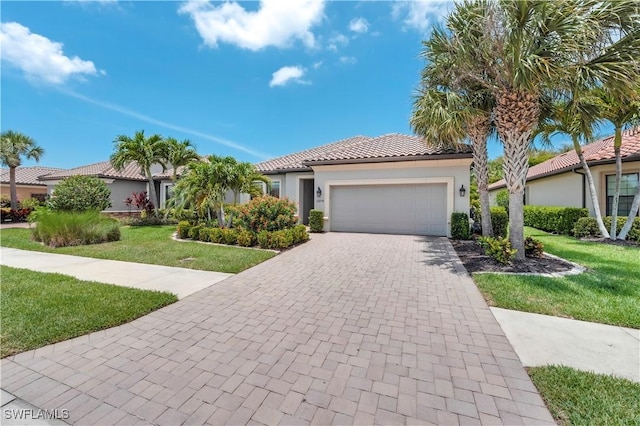 23778 Pebble Pointe Ln, Estero, FL 34135 - mediterranean / spanish house featuring a front lawn, stucco siding, an attached garage, a tile roof, and decorative driveway
