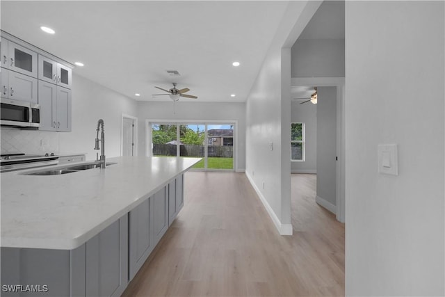 4201 17th St SW, Lehigh Acres, FL 33976 - kitchen featuring stainless steel microwave, ceiling fan, recessed lighting, light wood-style floors, and decorative backsplash