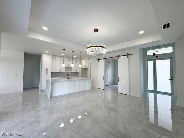 1009 Euclid Ave, Lehigh Acres, FL 33972 - kitchen with a raised ceiling, a barn door, baseboards, open floor plan, and light marble finish flooring