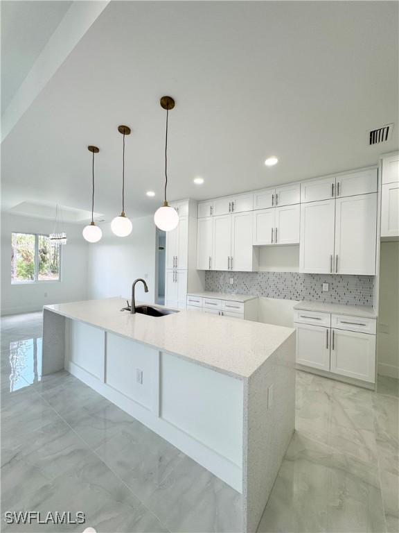 1009 Euclid Ave, Lehigh Acres, FL 33972 - kitchen with a sink, light marble finish floors, white cabinets, backsplash, and recessed lighting
