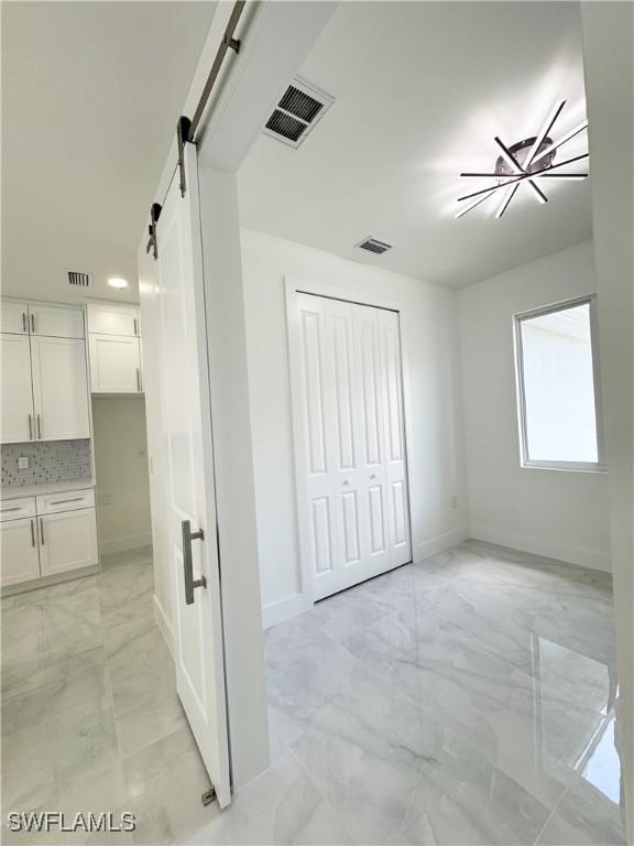 1009 Euclid Ave, Lehigh Acres, FL 33972 - unfurnished bedroom with light marble finish floors, baseboards, a barn door, and a closet