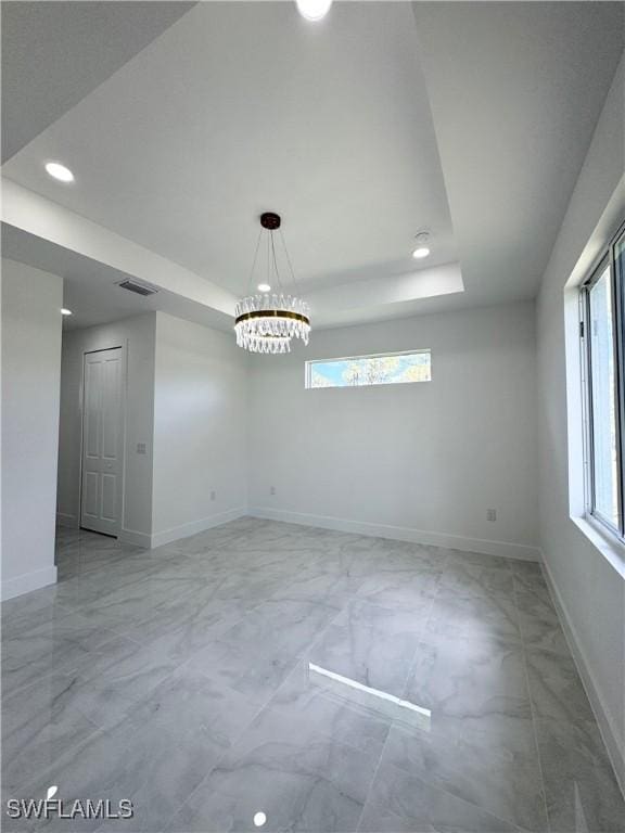1009 Euclid Ave, Lehigh Acres, FL 33972 - empty room featuring a tray ceiling, light marble finish flooring, baseboards, recessed lighting, and a chandelier