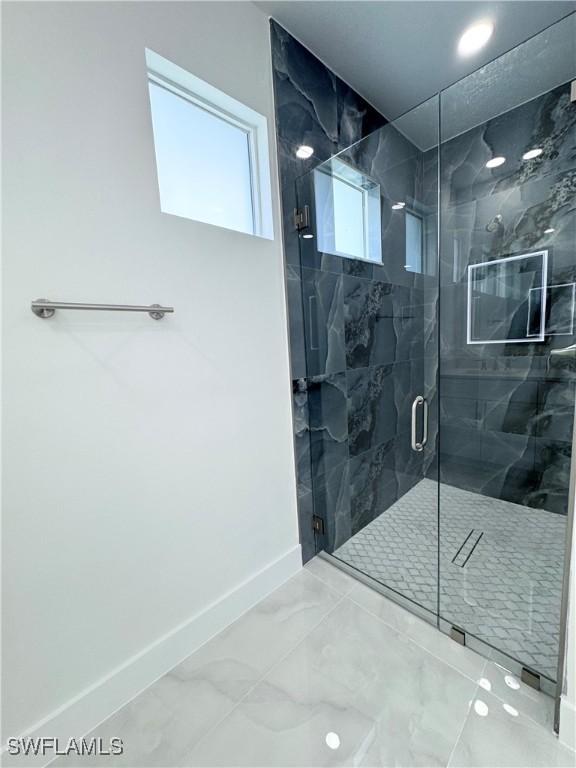 1009 Euclid Ave, Lehigh Acres, FL 33972 - bathroom featuring baseboards, marble finish flooring, and a marble finish shower