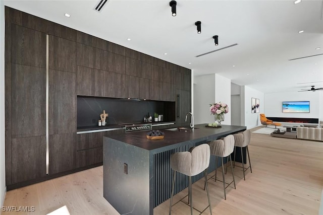 1135 Bluebird Ave, Marco Island, FL 34145 - kitchen featuring modern cabinets, a kitchen bar, light wood-style floors, and dark countertops