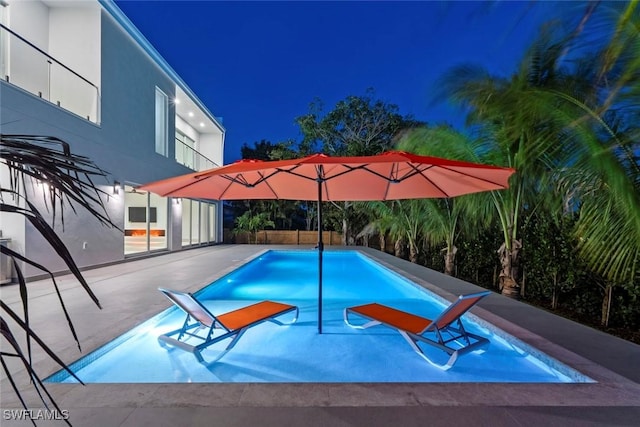 1135 Bluebird Ave, Marco Island, FL 34145 - pool at night with an outdoor pool, a fenced backyard, and a patio area
