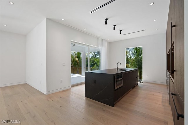 1135 Bluebird Ave, Marco Island, FL 34145 - kitchen featuring modern cabinets, a sink, a center island with sink, light wood finished floors, and stainless steel oven