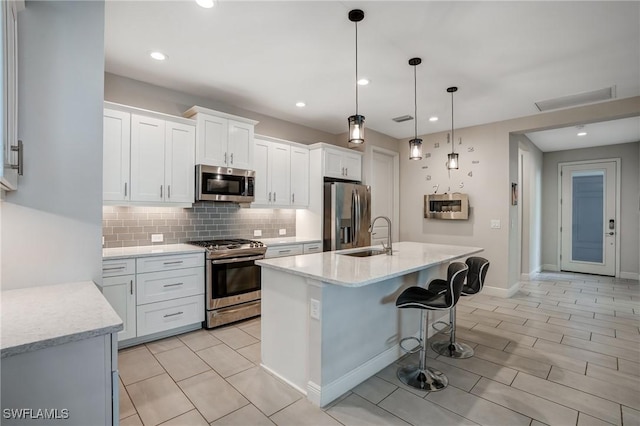7028 Mistral Way, Fort Myers, FL 33966 - kitchen with stainless steel appliances, backsplash, a sink, white cabinets, and an island with sink