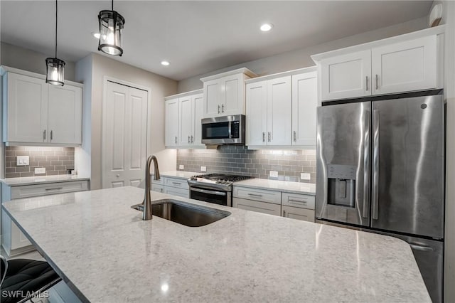 7028 Mistral Way, Fort Myers, FL 33966 - kitchen with stainless steel appliances, a sink, decorative backsplash, white cabinets, and light stone countertops