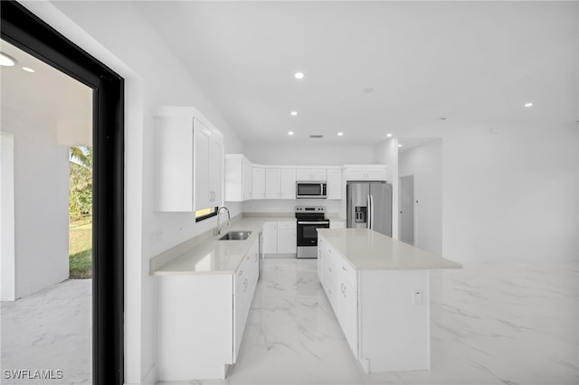 3201 14th St W, Lehigh Acres, FL 33971 - kitchen with stainless steel appliances, a sink, white cabinetry, a center island, and light marble finish floors