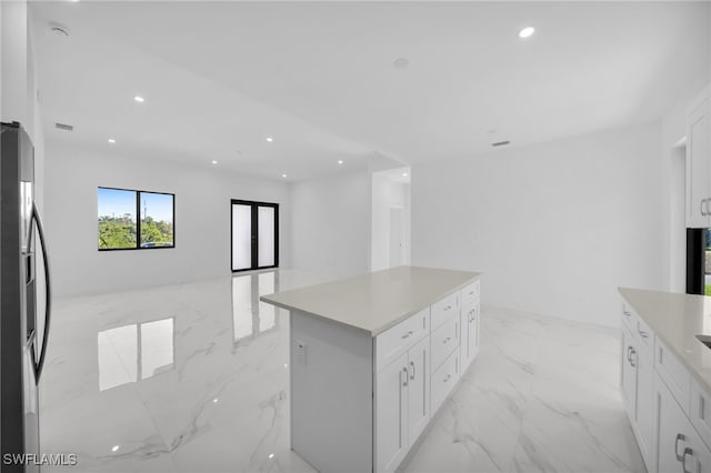 3201 14th St W, Lehigh Acres, FL 33971 - kitchen with refrigerator with ice dispenser, a kitchen island, white cabinetry, recessed lighting, and light marble finish flooring