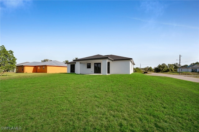 3201 14th St W, Lehigh Acres, FL 33971 - rear view of house with a lawn and stucco siding