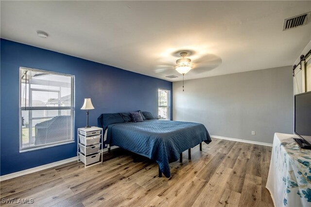 1812 SW 10th Ter, Cape Coral, FL 33991 - bedroom with a barn door, light wood finished floors, baseboards, and a ceiling fan