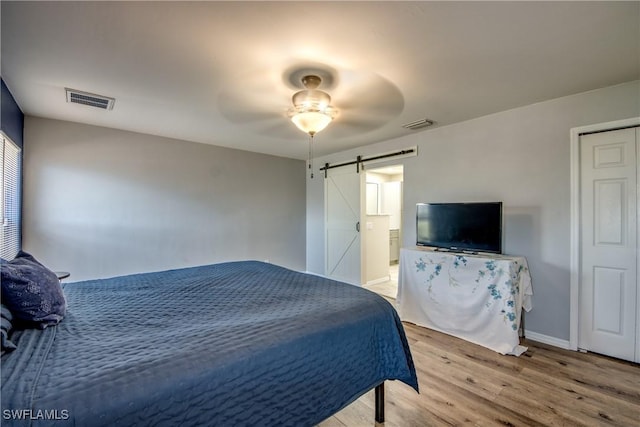 1812 SW 10th Ter, Cape Coral, FL 33991 - bedroom with a barn door, light wood-type flooring, baseboards, and a ceiling fan