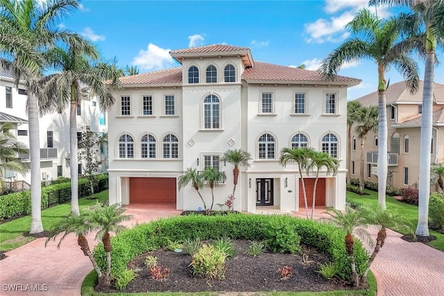 175 Topanga Dr, Bonita Springs, FL 34134 - mediterranean / spanish-style home with an attached garage, stucco siding, a tiled roof, and decorative driveway