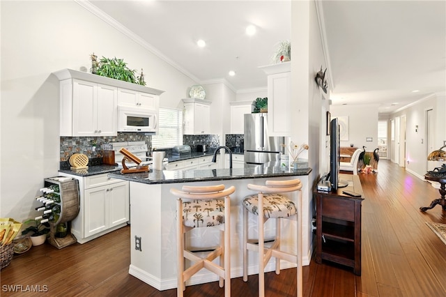 24712 Lakemont Cove Ln Unit 202, Bonita Springs, FL 34134 - kitchen with white microwave, freestanding refrigerator, dark wood-type flooring, tasteful backsplash, and a breakfast bar
