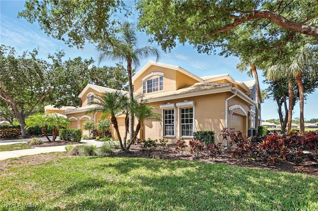 24712 Lakemont Cove Ln Unit 202, Bonita Springs, FL 34134 - view of front facade featuring a garage, stucco siding, and a front yard