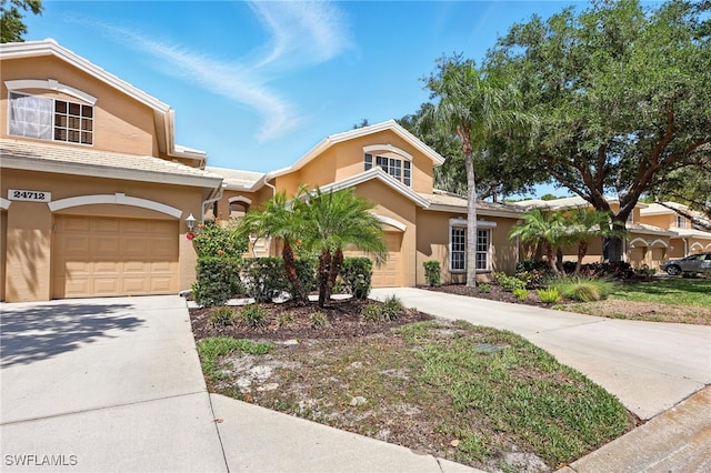 24712 Lakemont Cove Ln Unit 202, Bonita Springs, FL 34134 - view of front facade with an attached garage, driveway, and stucco siding