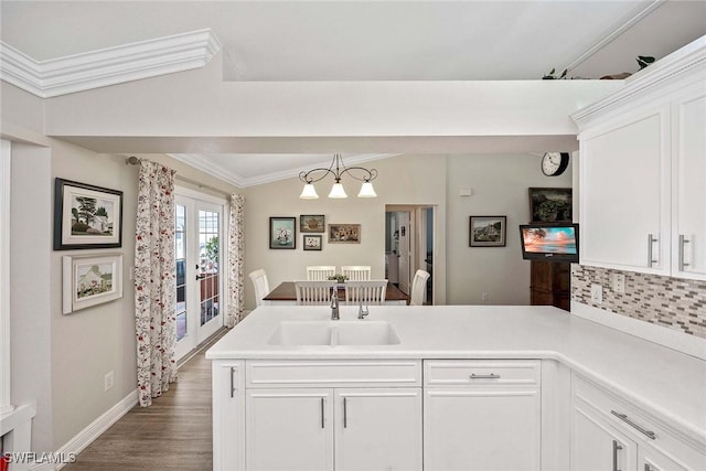 180 20th St SE, Naples, FL 34117 - kitchen with a sink, crown molding, a peninsula, backsplash, and white cabinets