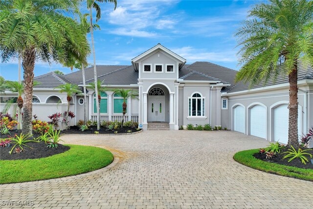 10072 Orchid Ridge Ln, Estero, FL 34135 - view of front facade featuring curved driveway, stucco siding, an attached garage, a tiled roof, and covered porch