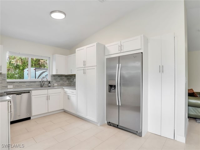 145 33rd Ave NE, Naples, FL 34120 - kitchen featuring appliances with stainless steel finishes, a sink, backsplash, vaulted ceiling, and white cabinetry