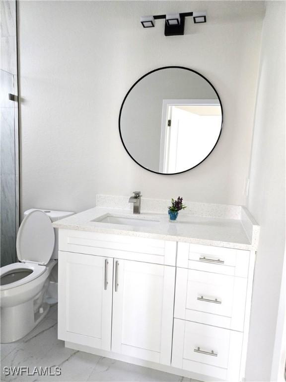 222 Victoria Ave S, Lehigh Acres, FL 33974 - bathroom with vanity, marble look tile flooring, and toilet