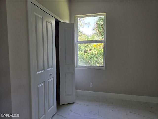 222 Victoria Ave S, Lehigh Acres, FL 33974 - unfurnished bedroom featuring marble finish floors, baseboards, and a closet