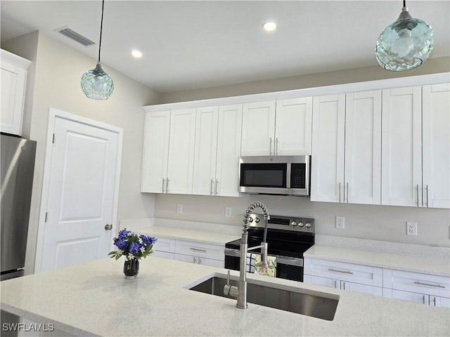222 Victoria Ave S, Lehigh Acres, FL 33974 - kitchen with stainless steel appliances, white cabinets, hanging light fixtures, recessed lighting, and light stone countertops