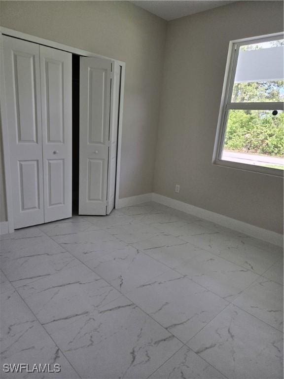 222 Victoria Ave S, Lehigh Acres, FL 33974 - unfurnished bedroom with light marble finish floors, baseboards, and a closet