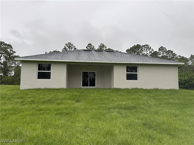 222 Victoria Ave S, Lehigh Acres, FL 33974 - back of house featuring a lawn, stucco siding, and roof with shingles