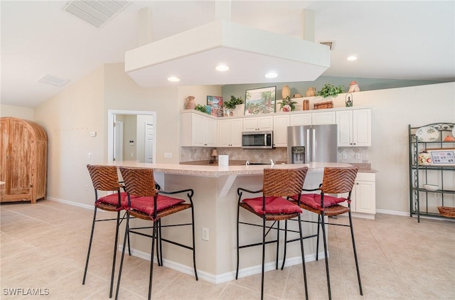 3708 SW 2nd Ln, Cape Coral, FL 33991 - kitchen featuring appliances with stainless steel finishes, vaulted ceiling, white cabinets, a breakfast bar area, and light countertops